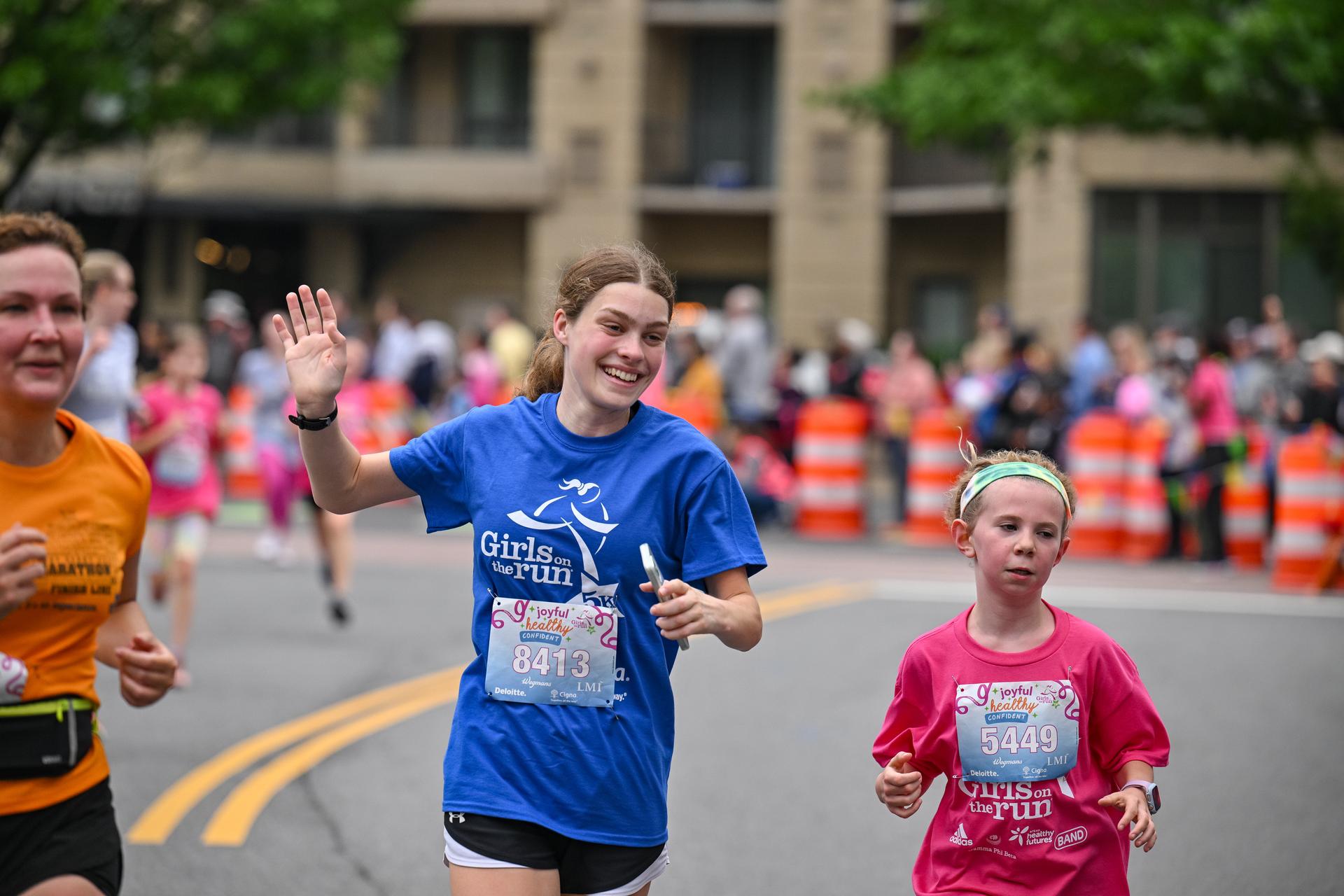 Three girls of varying ages from child to adult running at the 5K.