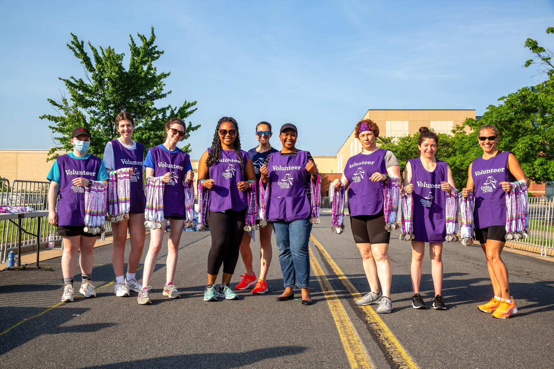 Group of 5K volunteers standing at the finish line with medals.