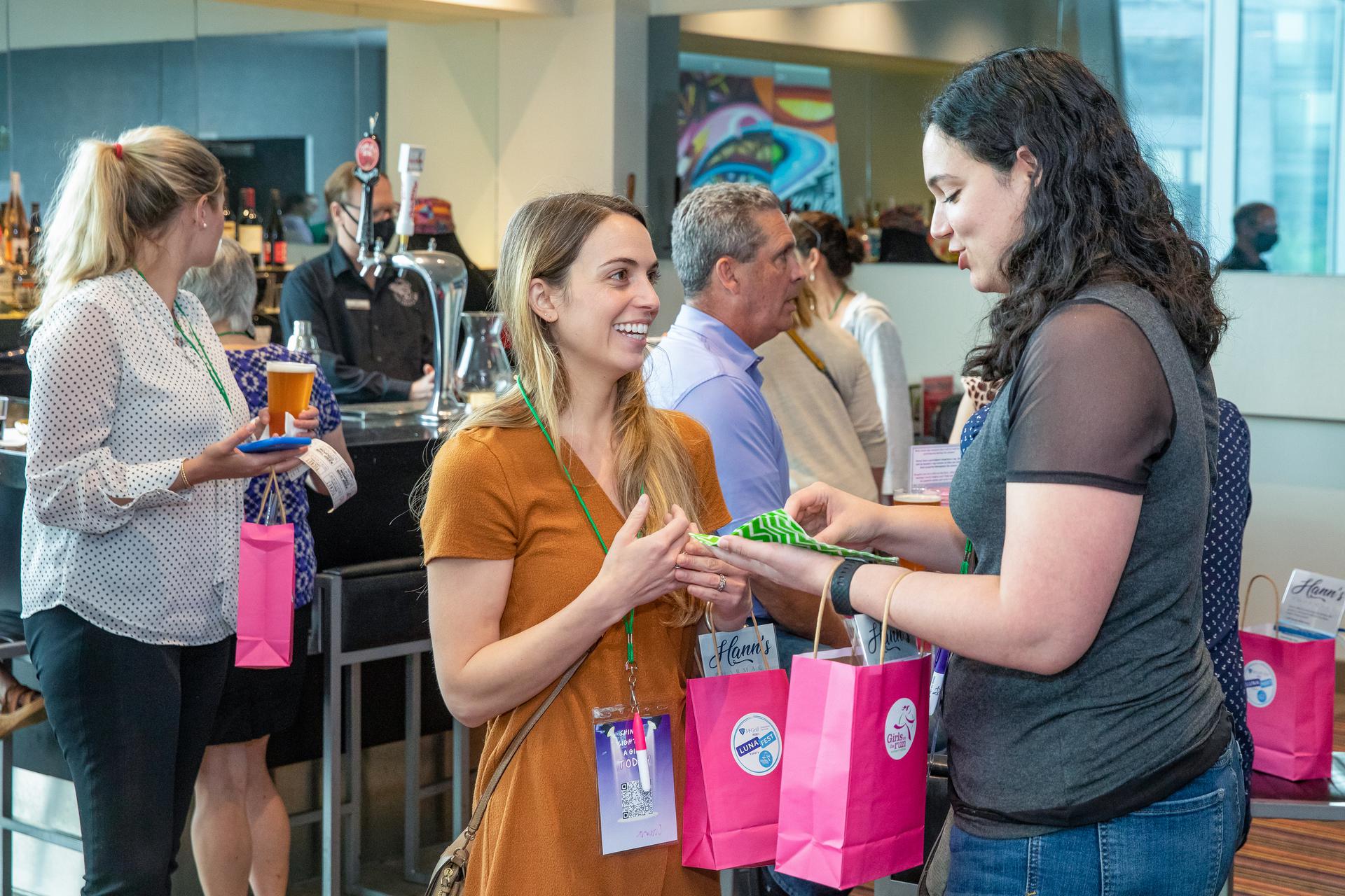 LUNAFEST attendees talking and holding their gift bags.