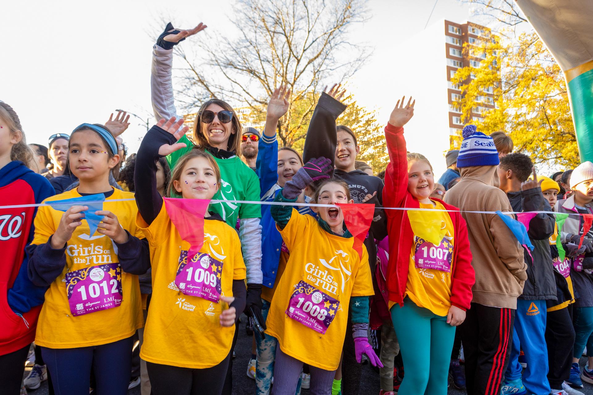 Two Girls on the Run participants holding up journals and smiling.