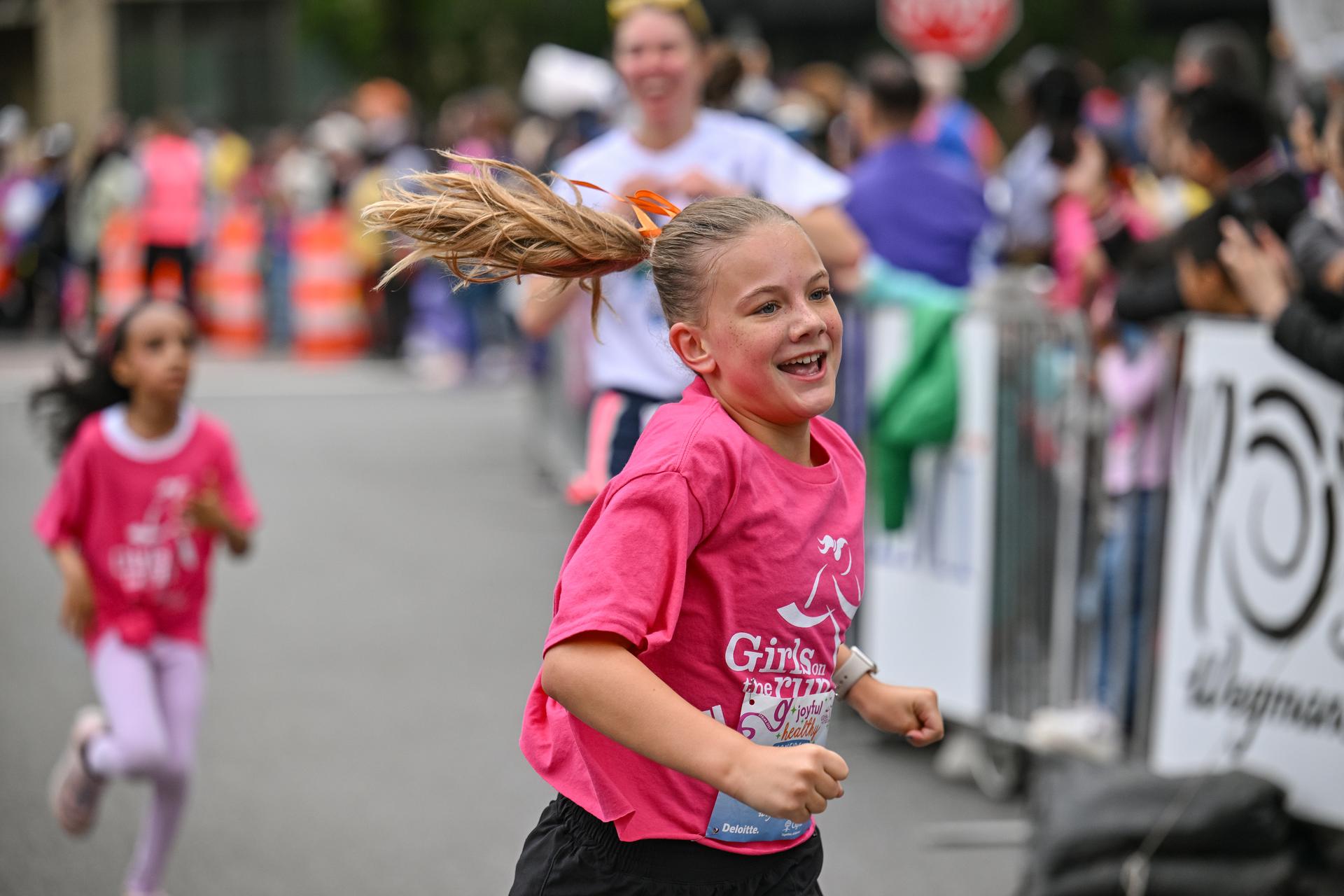 Girls on the Run participant running with a smile as she nears the finish line.