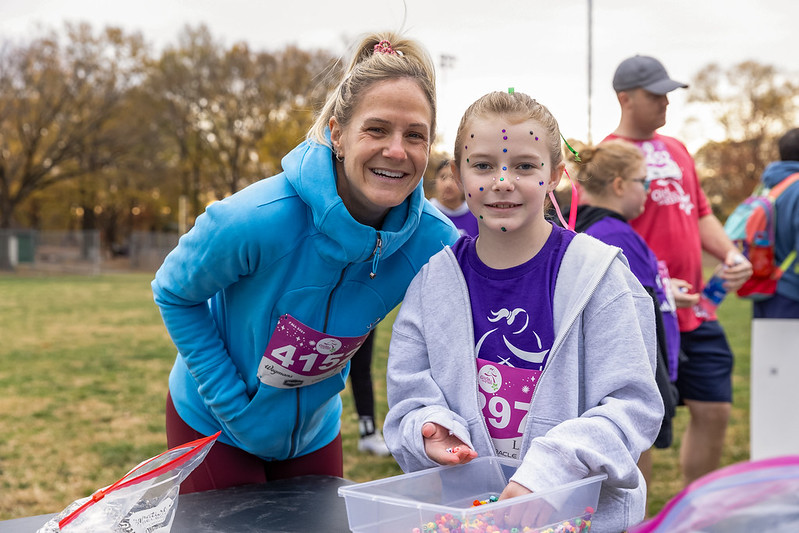 a Girls on the Run participant posing for a picture with their Buddy Runner at the 5K.