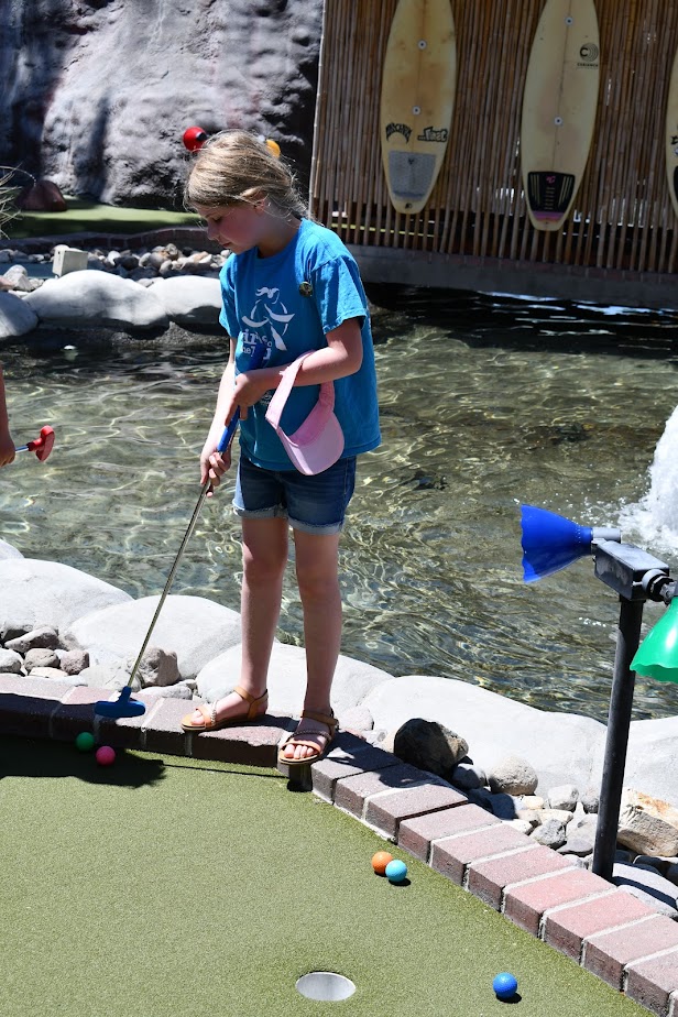 Girls on the Run participant playing mini golf in a Girls on the Run t-shirt.