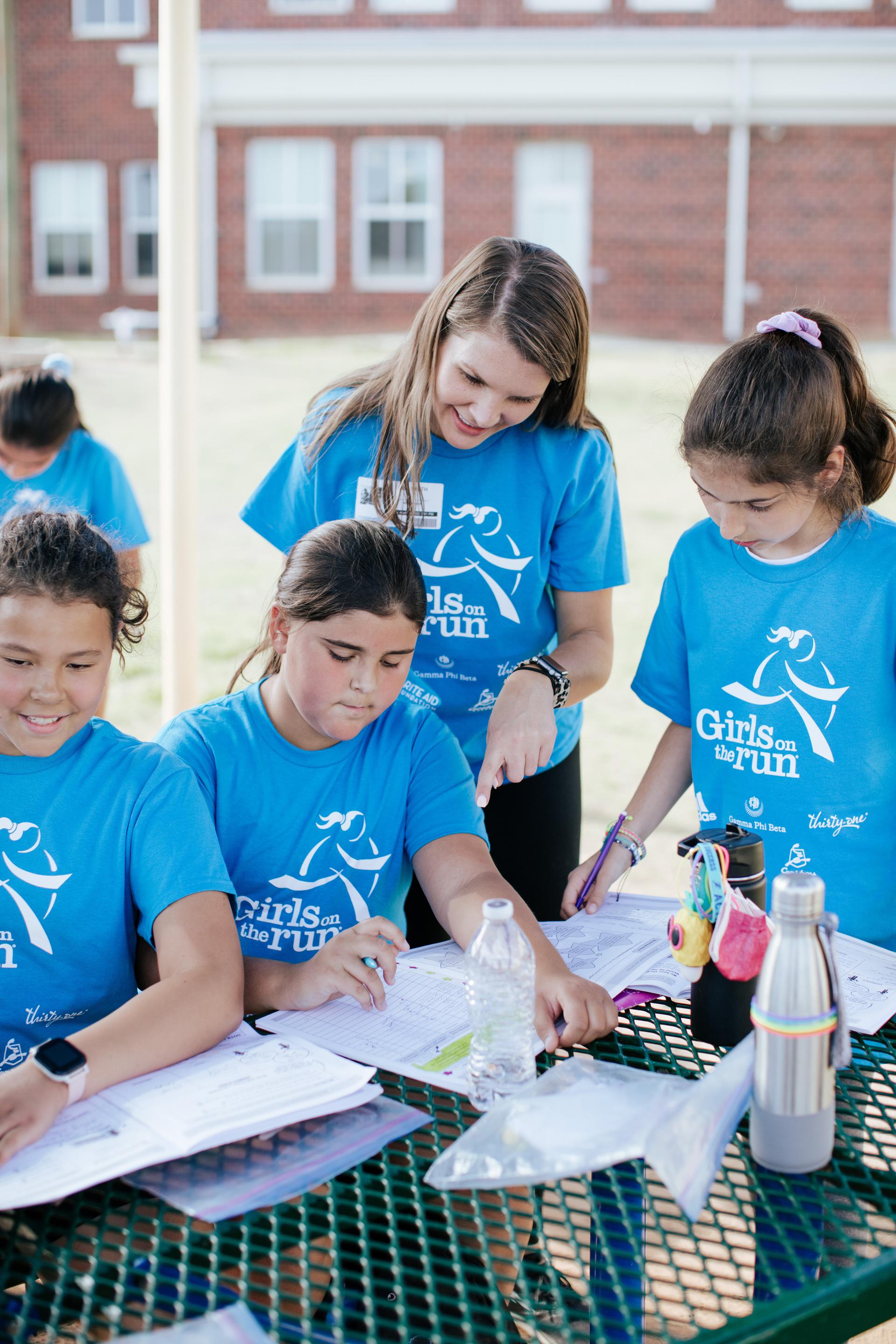 Group of Girls on the Run participants writing in their journals with a coach directing them.